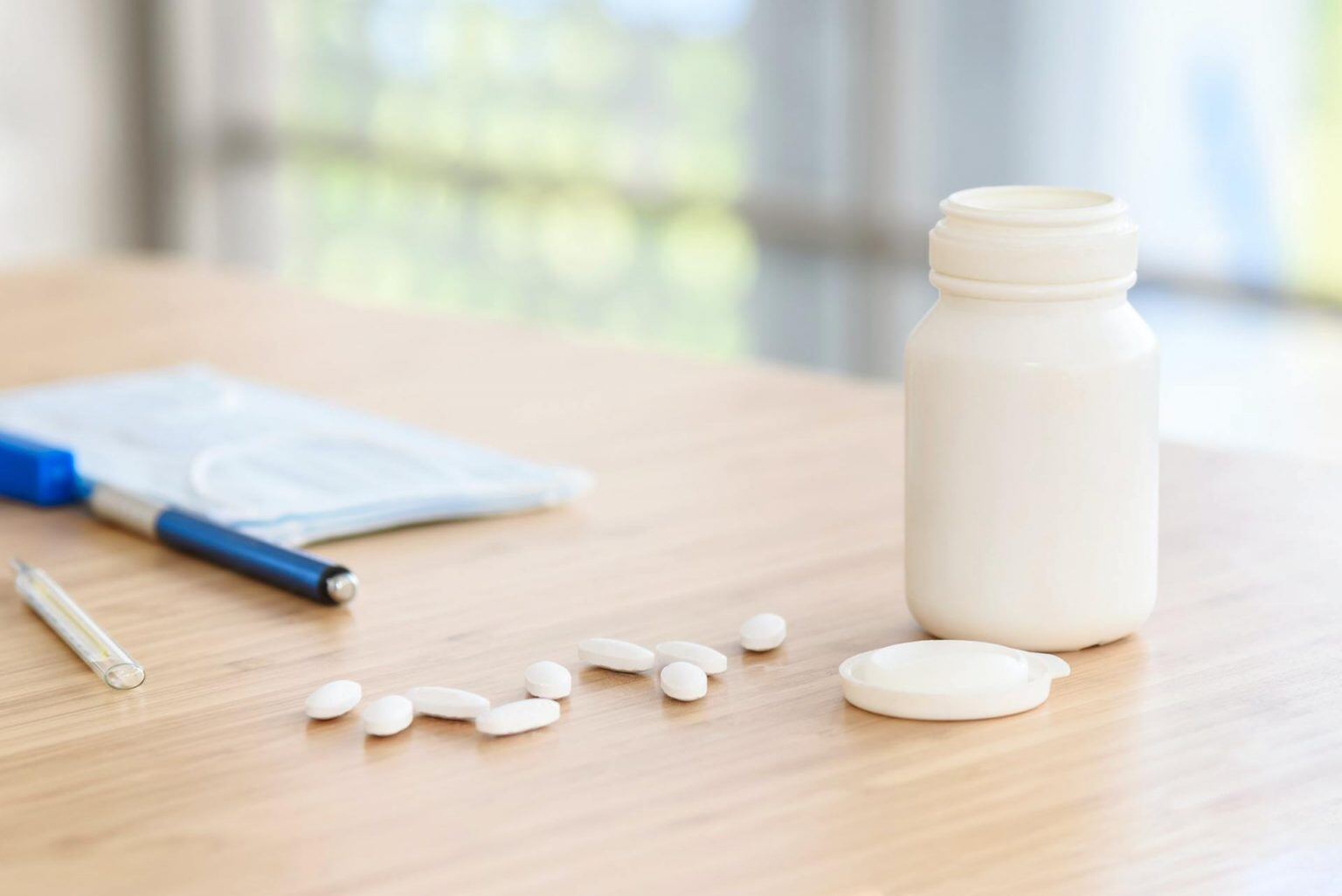 pills with white plastic medicine bottle on the table